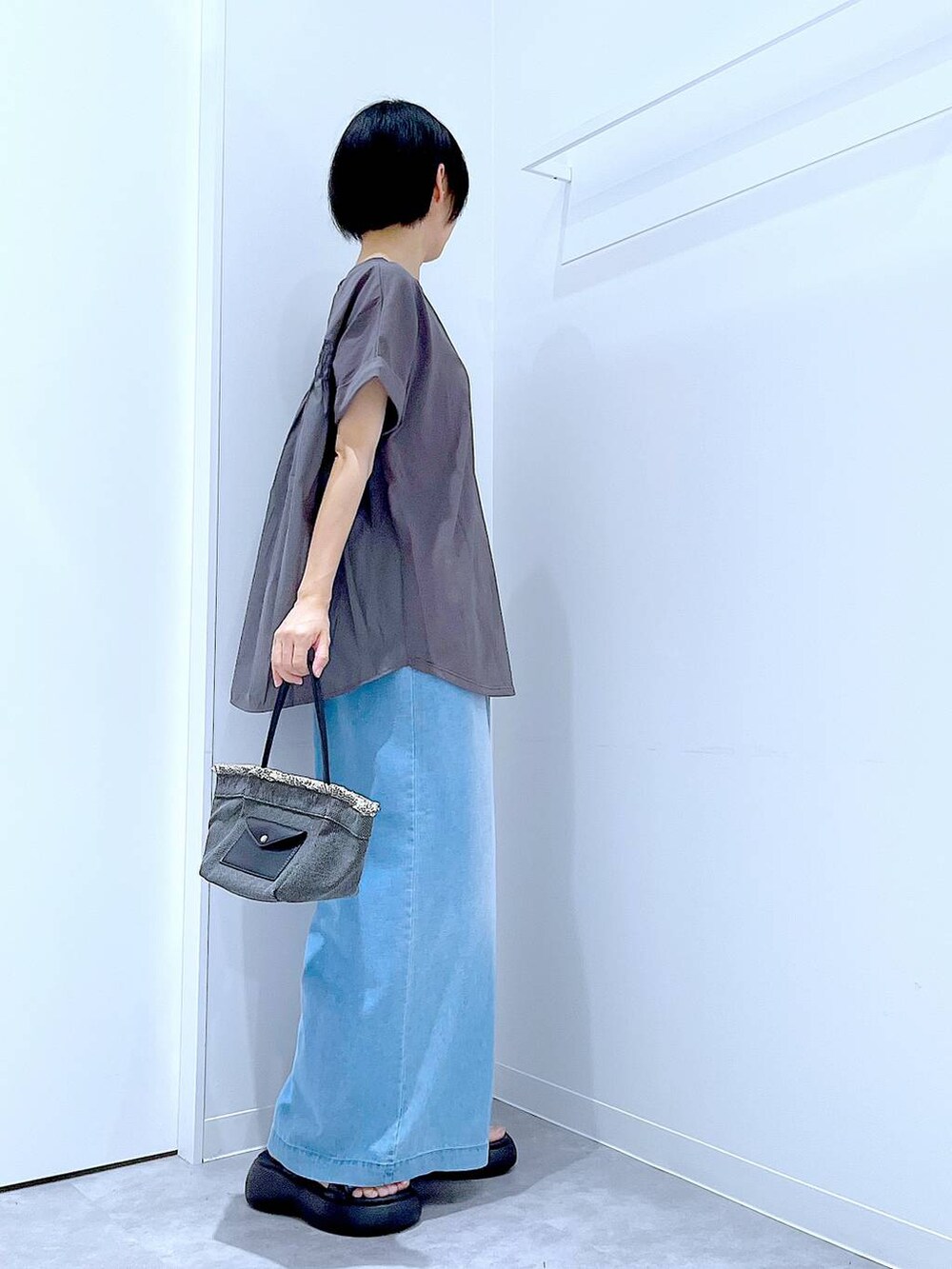 ブラック系のショルダーバッグ、ブラック系のサンダル、ブルー系のデニムパンツを着用したレディースの夏コーディネートの4枚目の写真