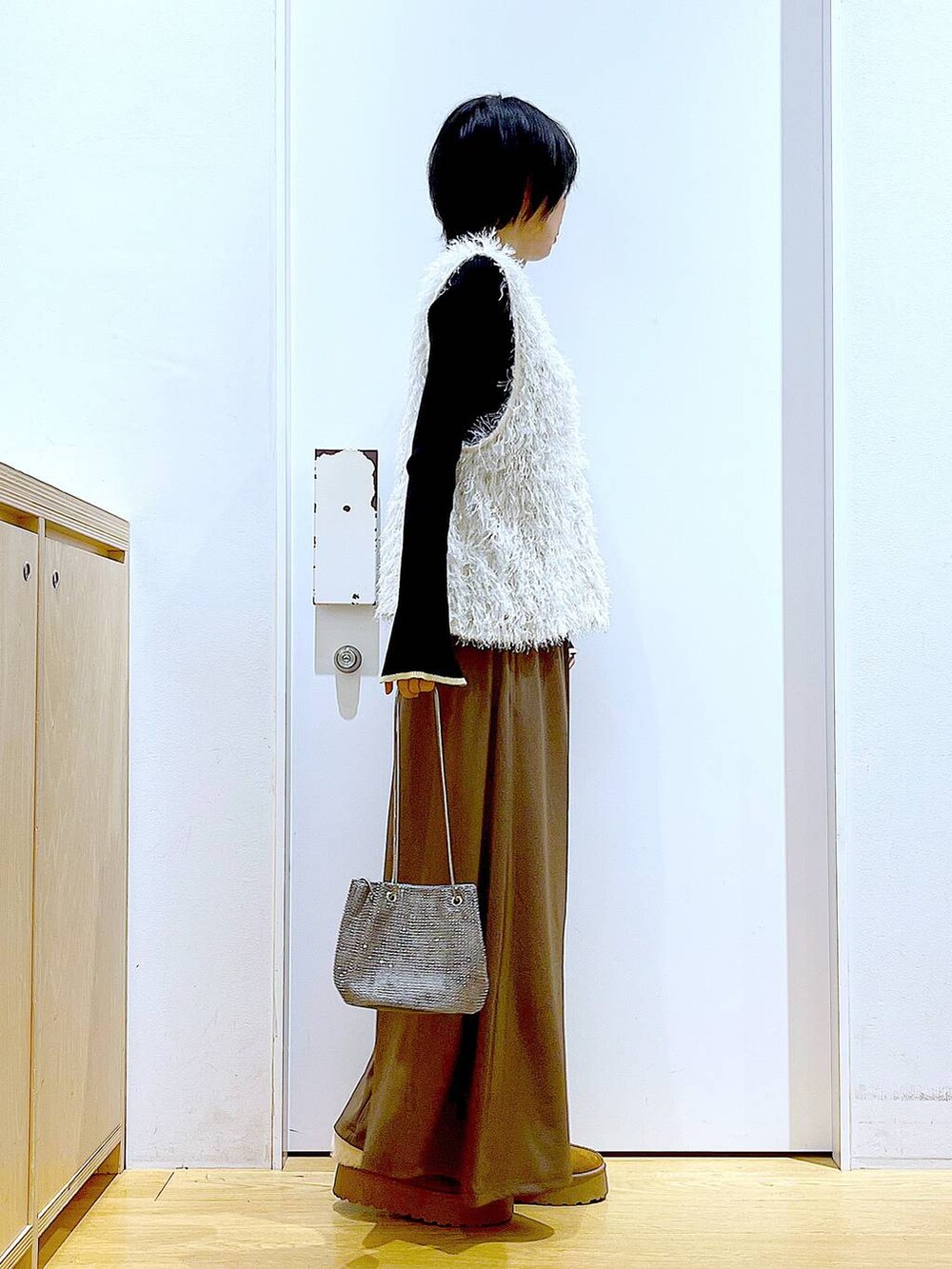 ブラック系のニット/セーター、グレー系のショルダーバッグ、ベージュ系のベストを着用したレディースの秋コーディネートの4枚目の写真