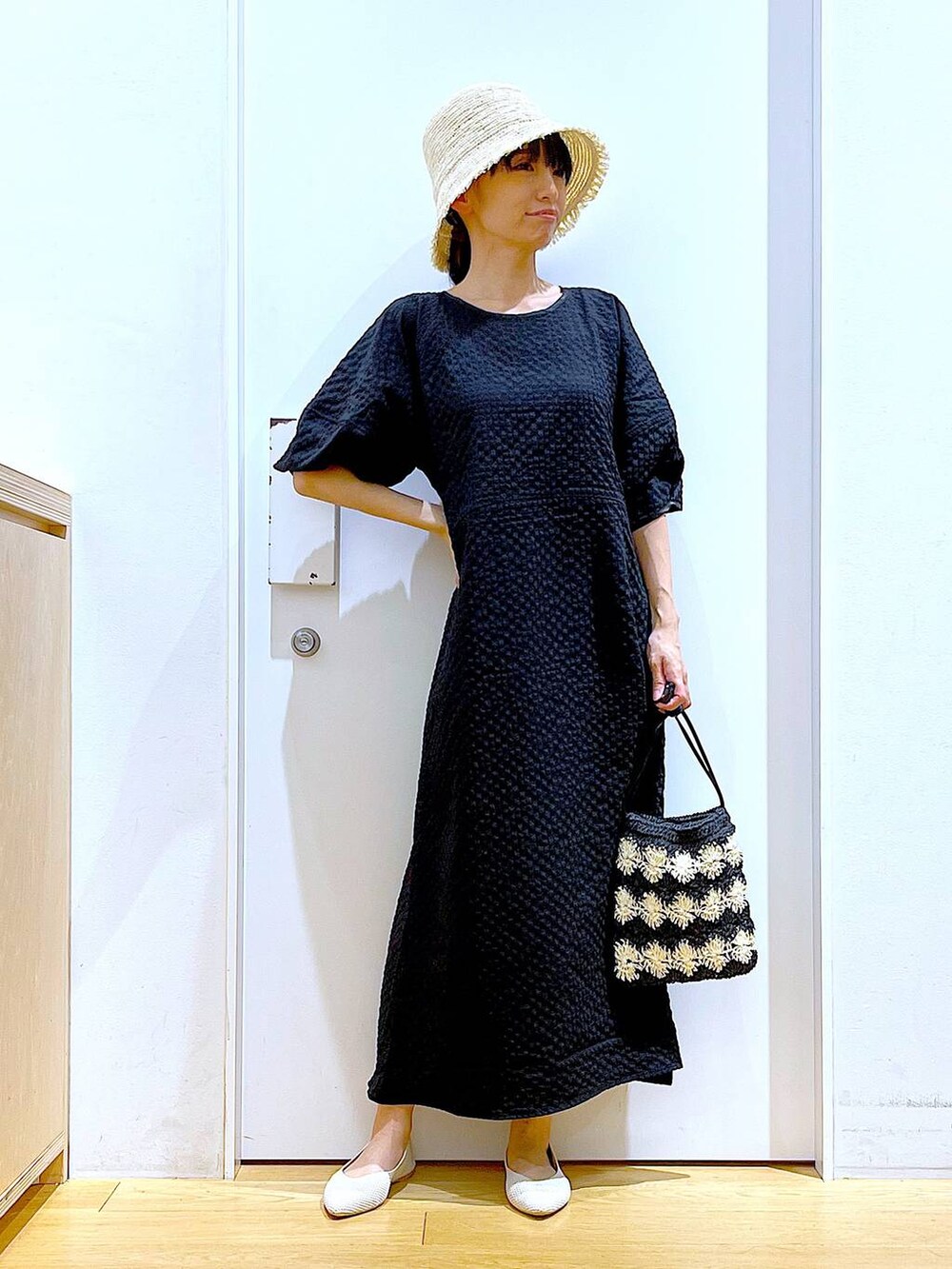 ホワイト系のパンプス、ブラック系のショルダーバッグ、ブラック系のワンピースを着用したレディースの夏コーディネートの2枚目の写真