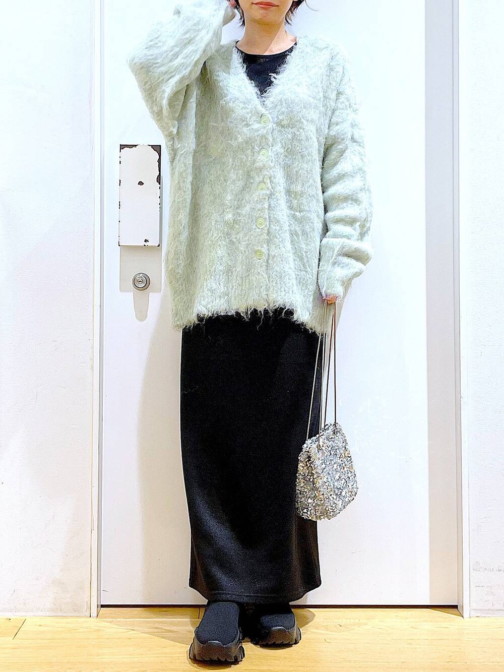 グリーン系のカーディガン/ボレロ、ブラック系のブーツ、ブラック系のスカートを着用したレディースの冬コーディネートの6枚目の写真
