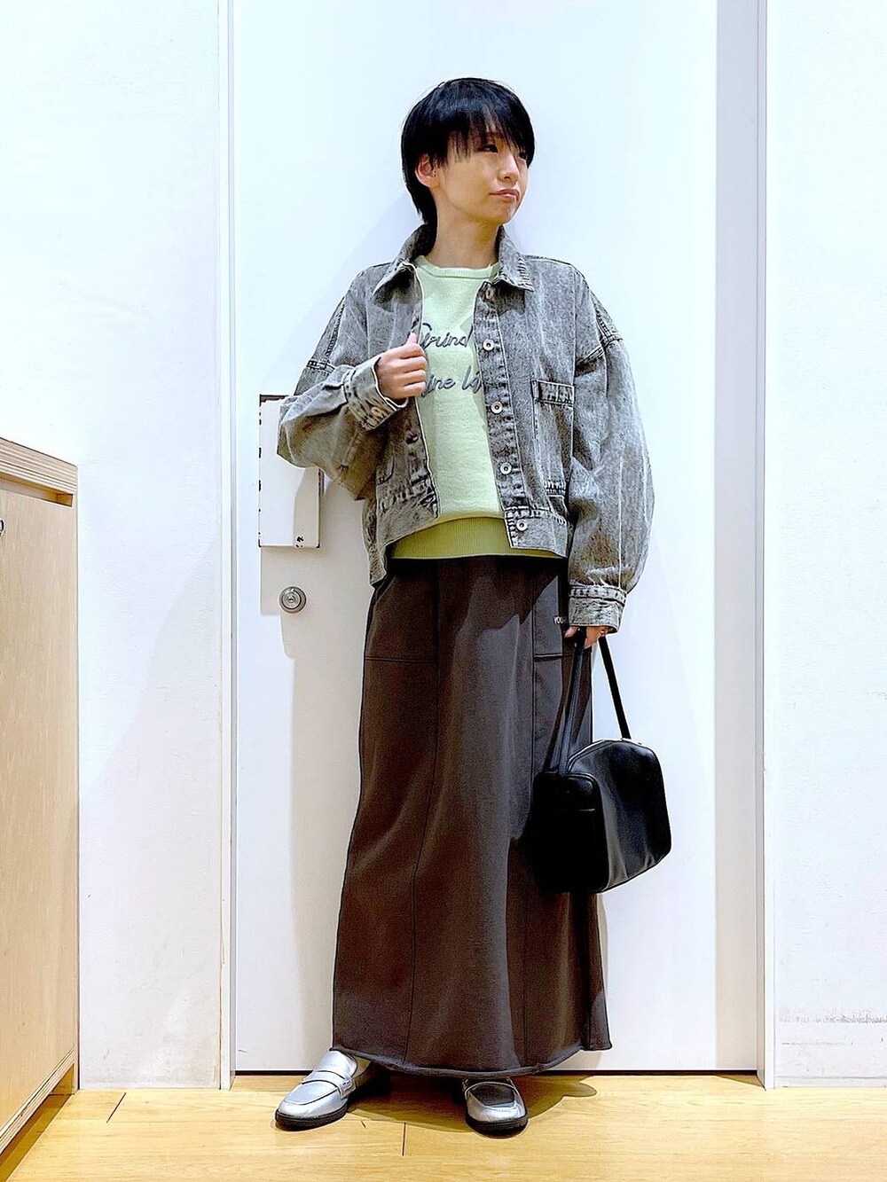 ブラック系のショルダーバッグ、シルバー系のローファー、ブラック系のデニムジャケットを着用したレディースの春コーディネートの2枚目の写真