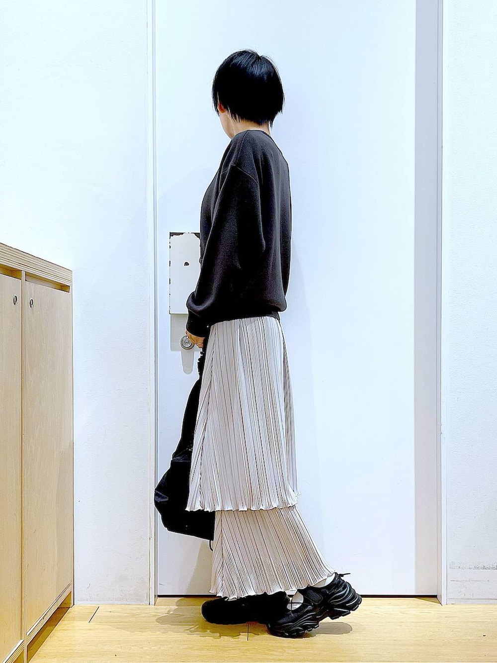 ブラック系のショルダーバッグ、ブラック系のスニーカー、グレー系のニット/セーターを着用したレディースの夏コーディネートの3枚目の写真