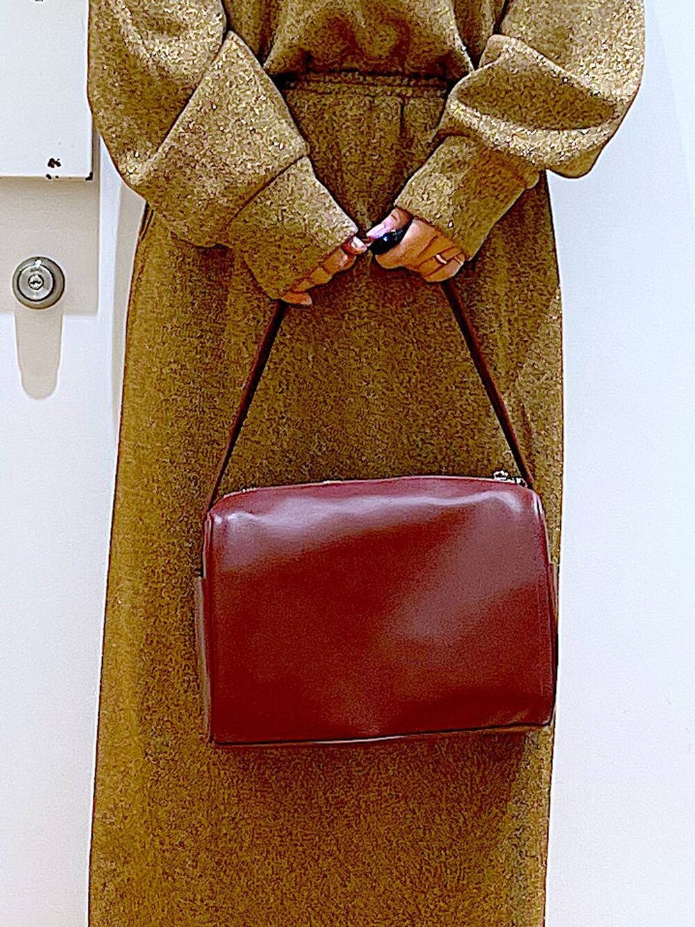 レッド系のショルダーバッグ、ブラック系のブーツ、ブラウン系のスウェットを着用したレディースの冬コーディネートの9枚目の写真