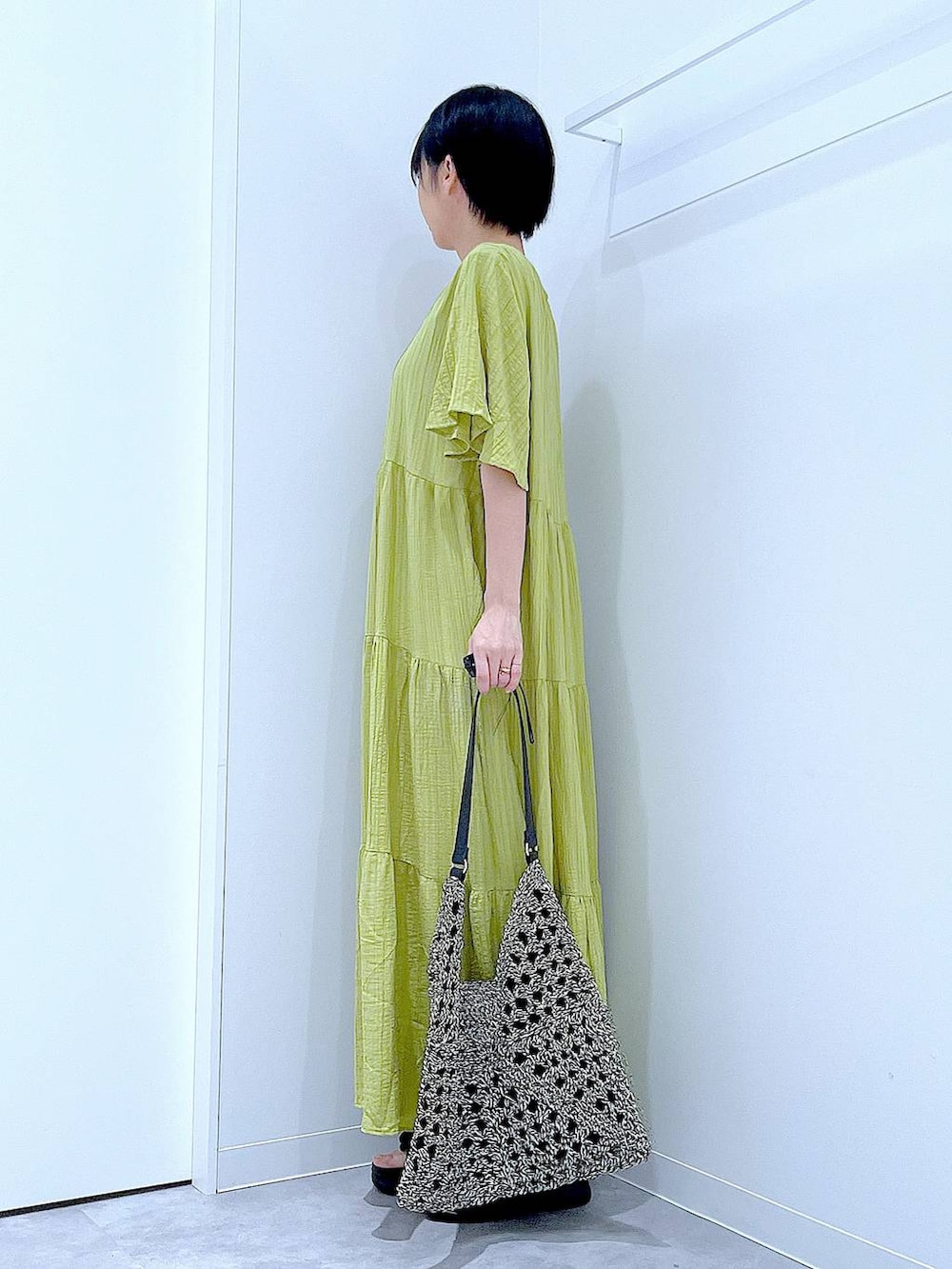 ブラック系のトートバッグ、ブラック系のサンダル、グリーン系のワンピースを着用したレディースの夏コーディネートの3枚目の写真