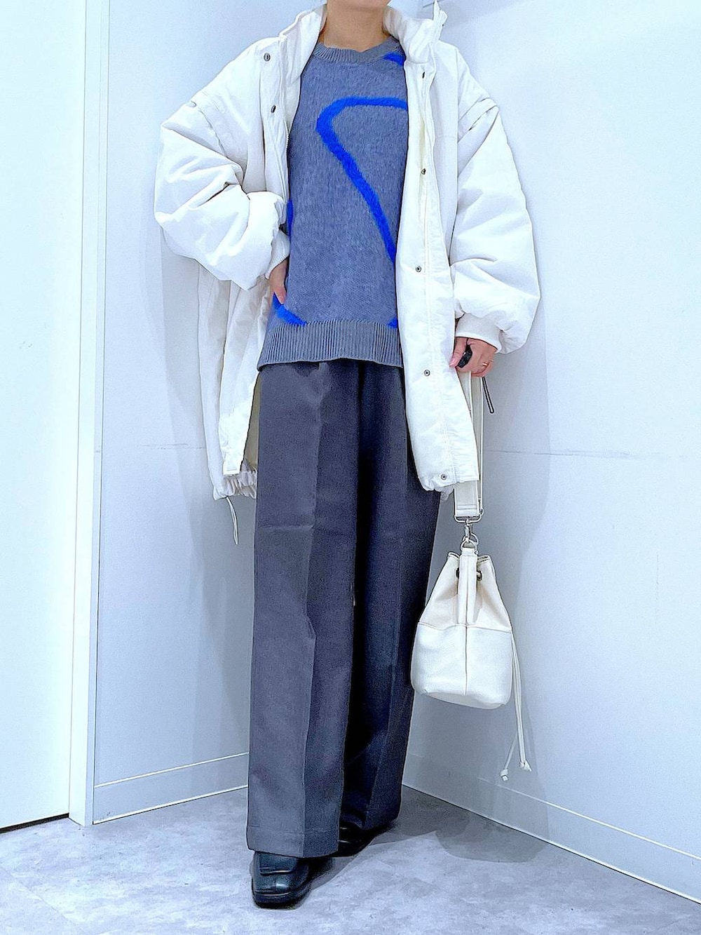 ホワイト系のブルゾン、ホワイト系のショルダーバッグ、ブラック系のブーツを着用したレディースの冬コーディネートの6枚目の写真