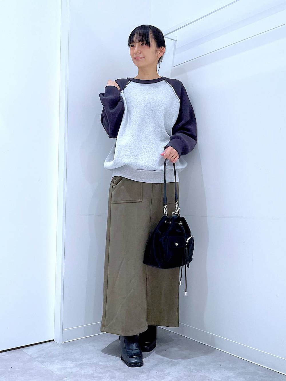 ブラック系のショルダーバッグ、グレー系のニット/セーター、ブラック系のブーツを着用したレディースの冬コーディネートの2枚目の写真