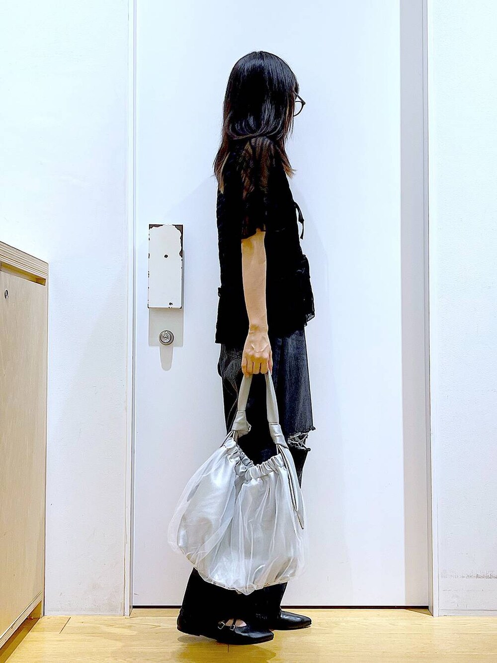 シルバー系のトートバッグ、ブラック系のデニムパンツ、ブラック系のカーディガン/ボレロを着用したレディースの秋コーディネートの4枚目の写真