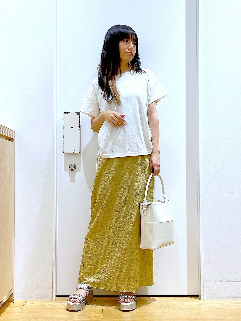 シルバー系のサンダル、ホワイト系のショルダーバッグ、グリーン系のスカートを着用したレディースの夏コーディネートの2枚目の写真