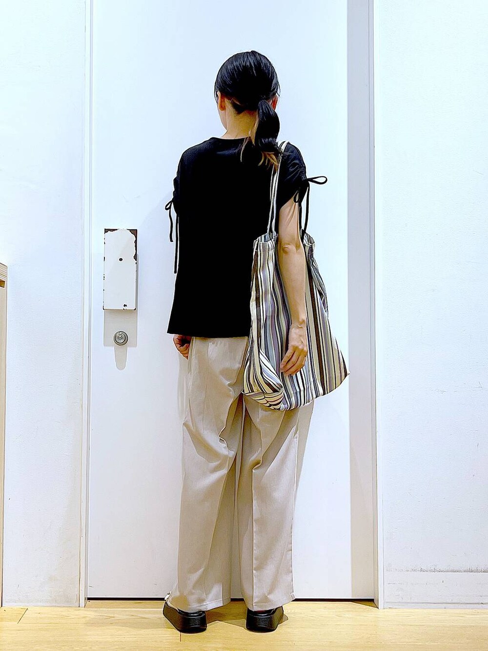 ホワイト系のサンダル、グリーン系のトートバッグ、ベージュ系のスラックスを着用したレディースの秋コーディネートの5枚目の写真