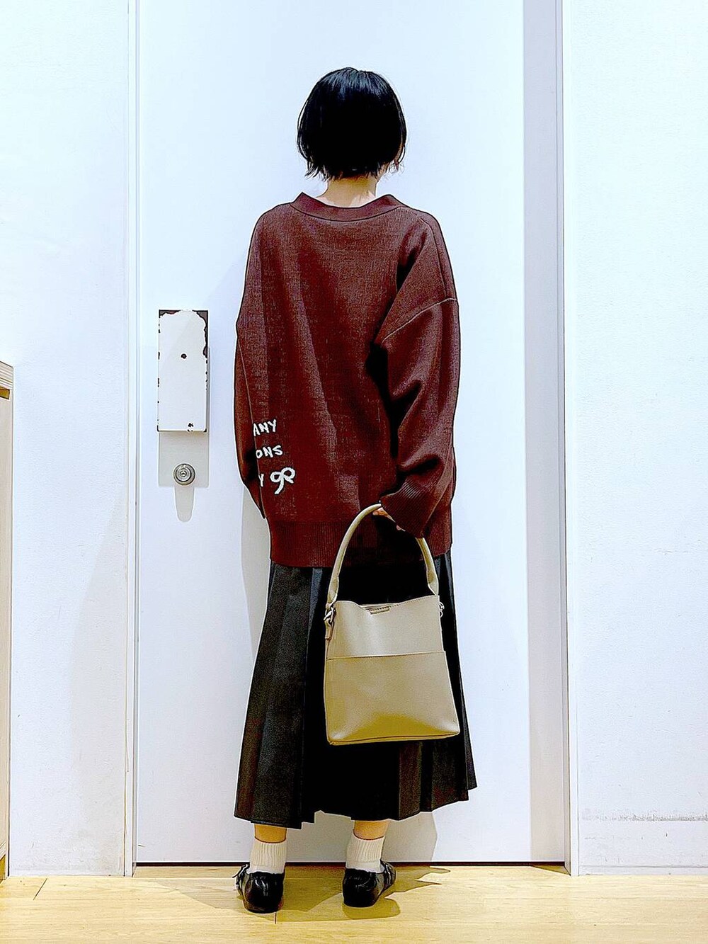 ブラック系のパンプス、ブラック系のスカート、ベージュ系のショルダーバッグを着用したレディースの秋コーディネートの5枚目の写真