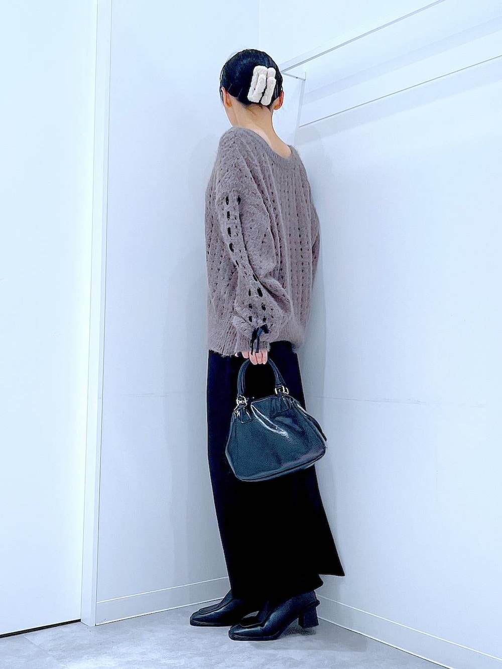 ブラック系のブーツ、ブラック系のショルダーバッグ、ベージュ系のニット/セーターを着用したレディースの冬コーディネートの3枚目の写真