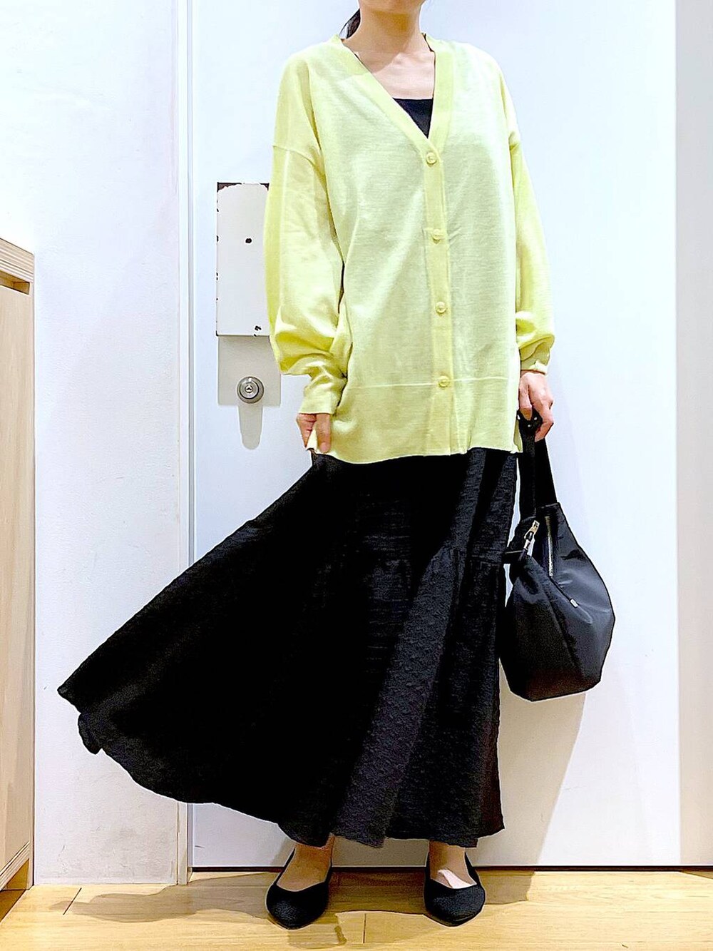 ブラック系のワンピース、グリーン系のカーディガン/ボレロ、ブラック系のショルダーバッグを着用したレディースの春コーディネートの6枚目の写真