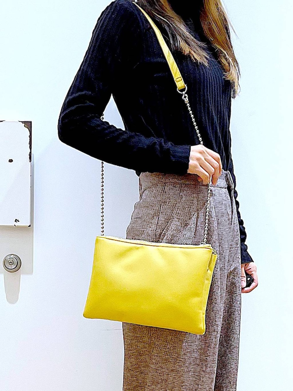 イエロー系のショルダーバッグ、ブラック系のブーツ、ブラウン系のその他パンツを着用したレディースの冬コーディネートの9枚目の写真