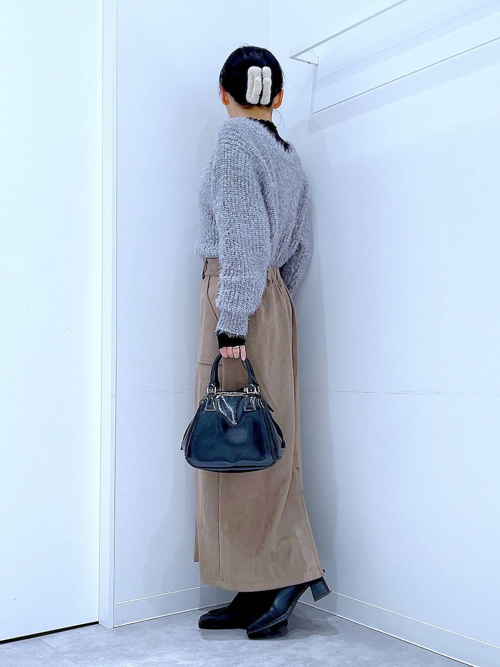 ブラック系のブーツ、ブラック系のショルダーバッグ、ブラウン系のスカートを着用したレディースの冬コーディネートの3枚目の写真