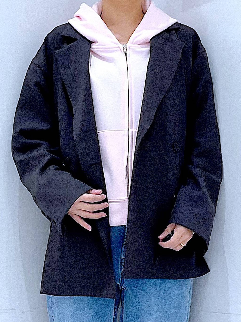 グレー系のテーラードジャケット、ブルー系のデニムパンツ、ピンク系のパーカーを着用したレディースの春コーディネートの7枚目の写真