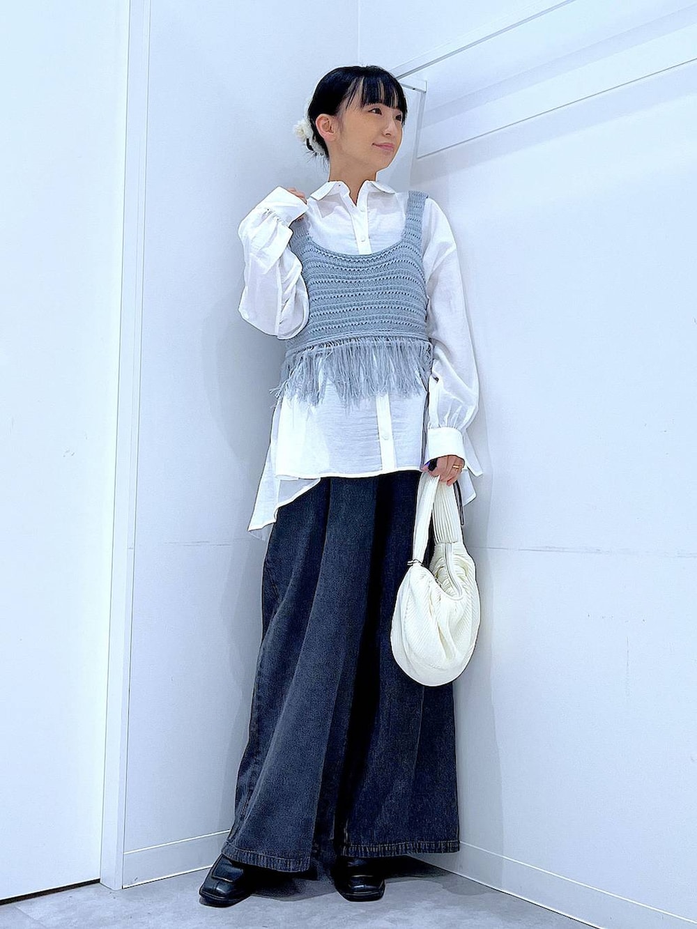 ブラック系のブーツ、ブルー系のベスト、ホワイト系のショルダーバッグを着用したレディースの春コーディネートの2枚目の写真