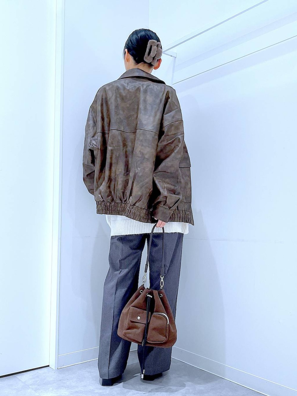 ブラウン系のブルゾン、ブラウン系のショルダーバッグ、ブラック系のブーツを着用したレディースの冬コーディネートの5枚目の写真