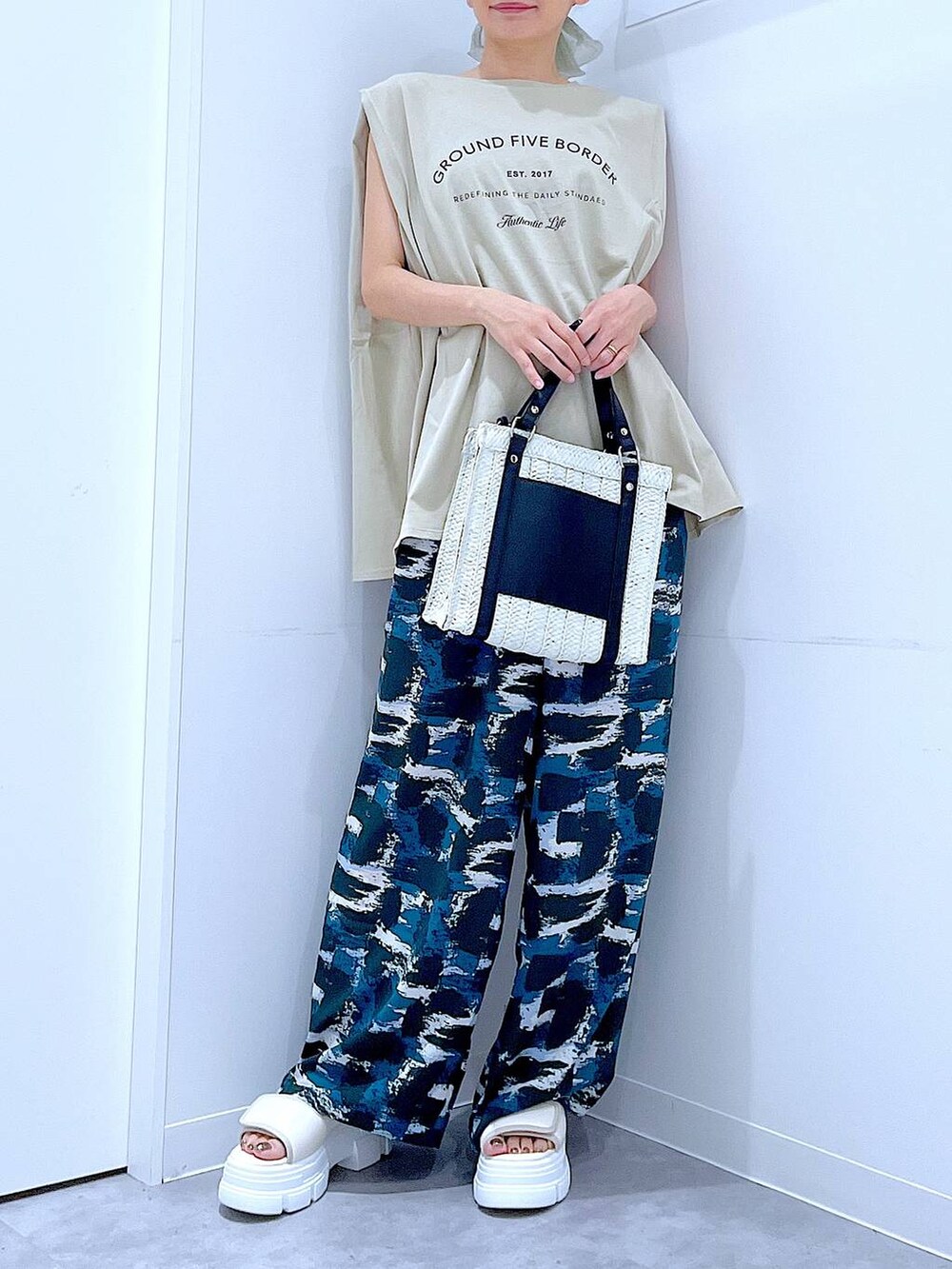 ホワイト系のショルダーバッグ、ホワイト系のサンダル、ベージュ系のTシャツ/カットソーを着用したレディースの夏コーディネートの6枚目の写真