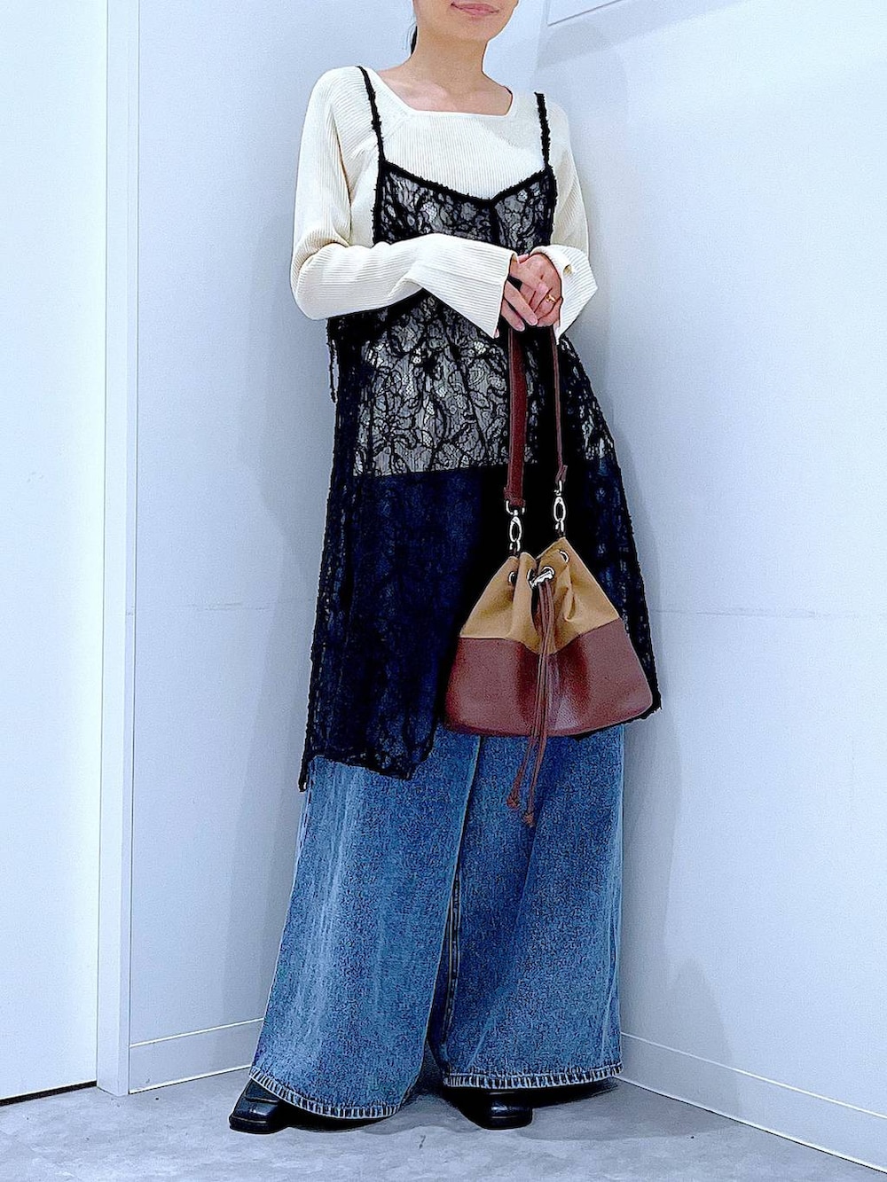 ベージュ系のニット/セーター、ブルー系のデニムパンツ、ベージュ系のショルダーバッグを着用したレディースの秋コーディネートの6枚目の写真