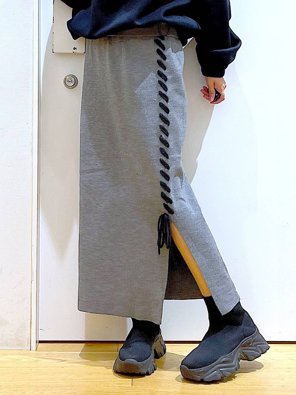 ブラック系のハンドバッグ、ブラック系のブーツ、グレー系のスカートを着用したレディースの冬コーディネートの8枚目の写真