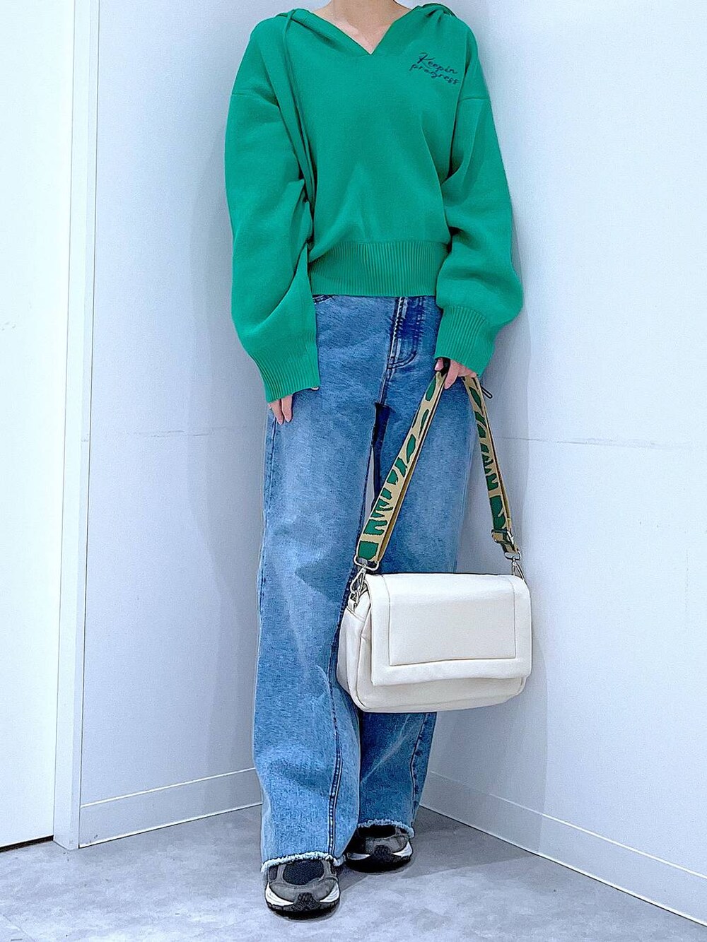 ホワイト系のショルダーバッグ、グリーン系のニット/セーター、ブルー系のデニムパンツを着用したレディースの春コーディネートの6枚目の写真