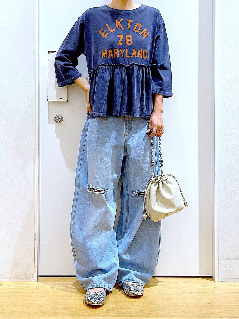 ブラック系のショルダーバッグ、ブルー系のデニムパンツ、シルバー系のパンプスを着用したレディースの秋コーディネートの6枚目の写真