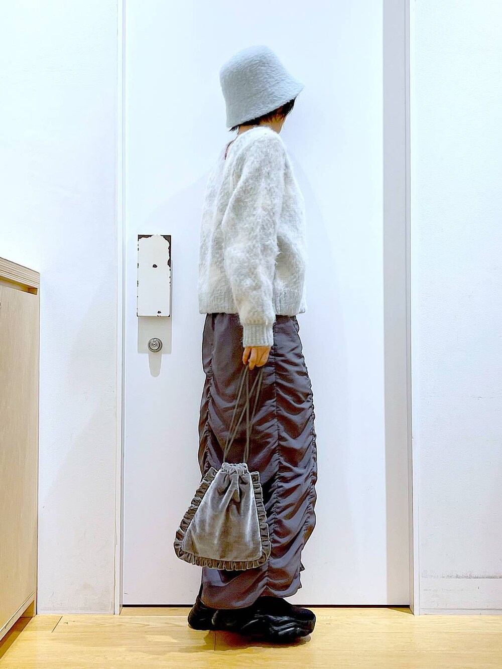 グレー系のショルダーバッグ、グレー系のスカート、ブラック系のブーツを着用したレディースの冬コーディネートの4枚目の写真