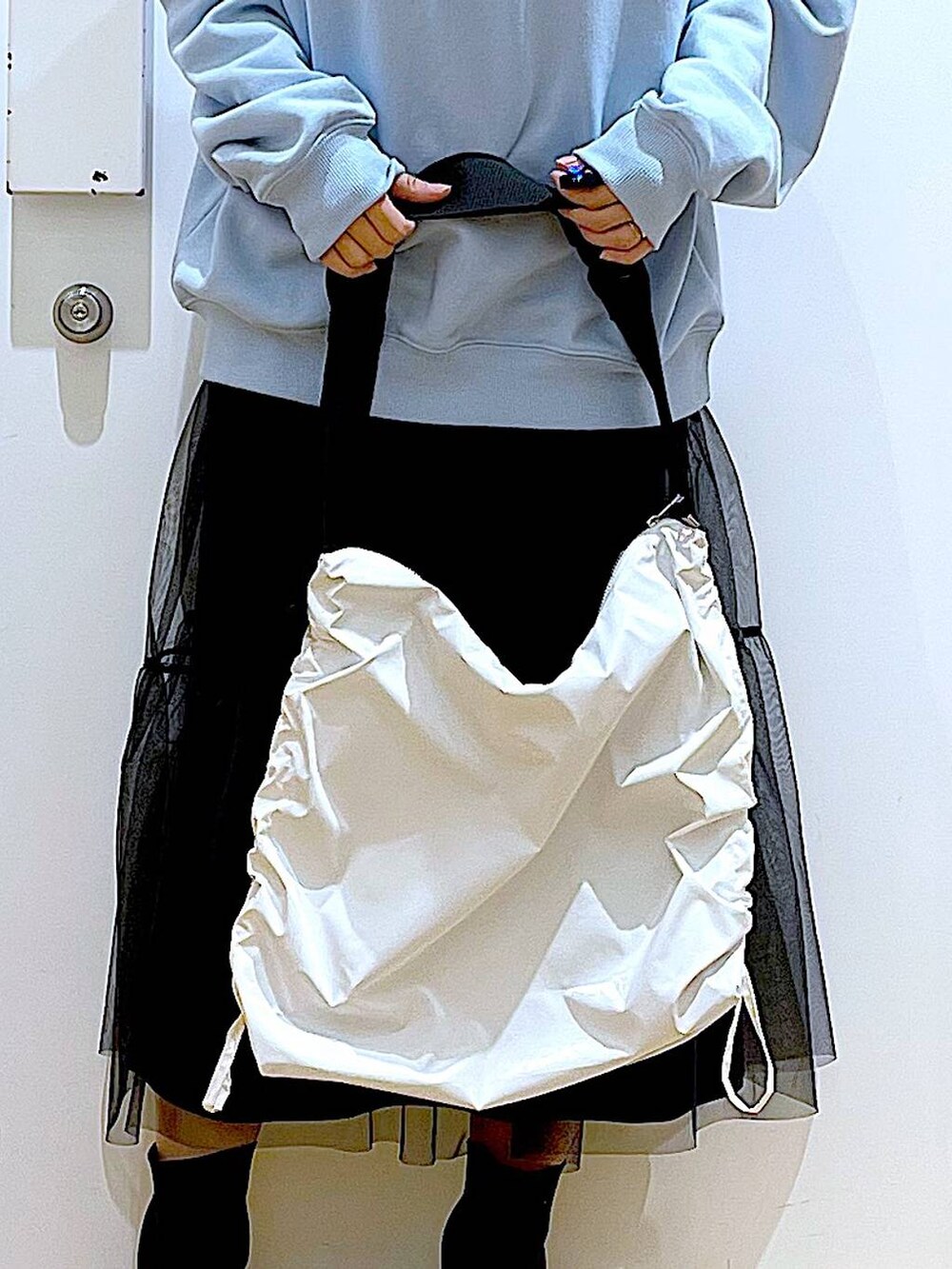 ブルー系のスウェット、ブラック系のブーツ、ホワイト系のショルダーバッグを着用したレディースの春コーディネートの9枚目の写真