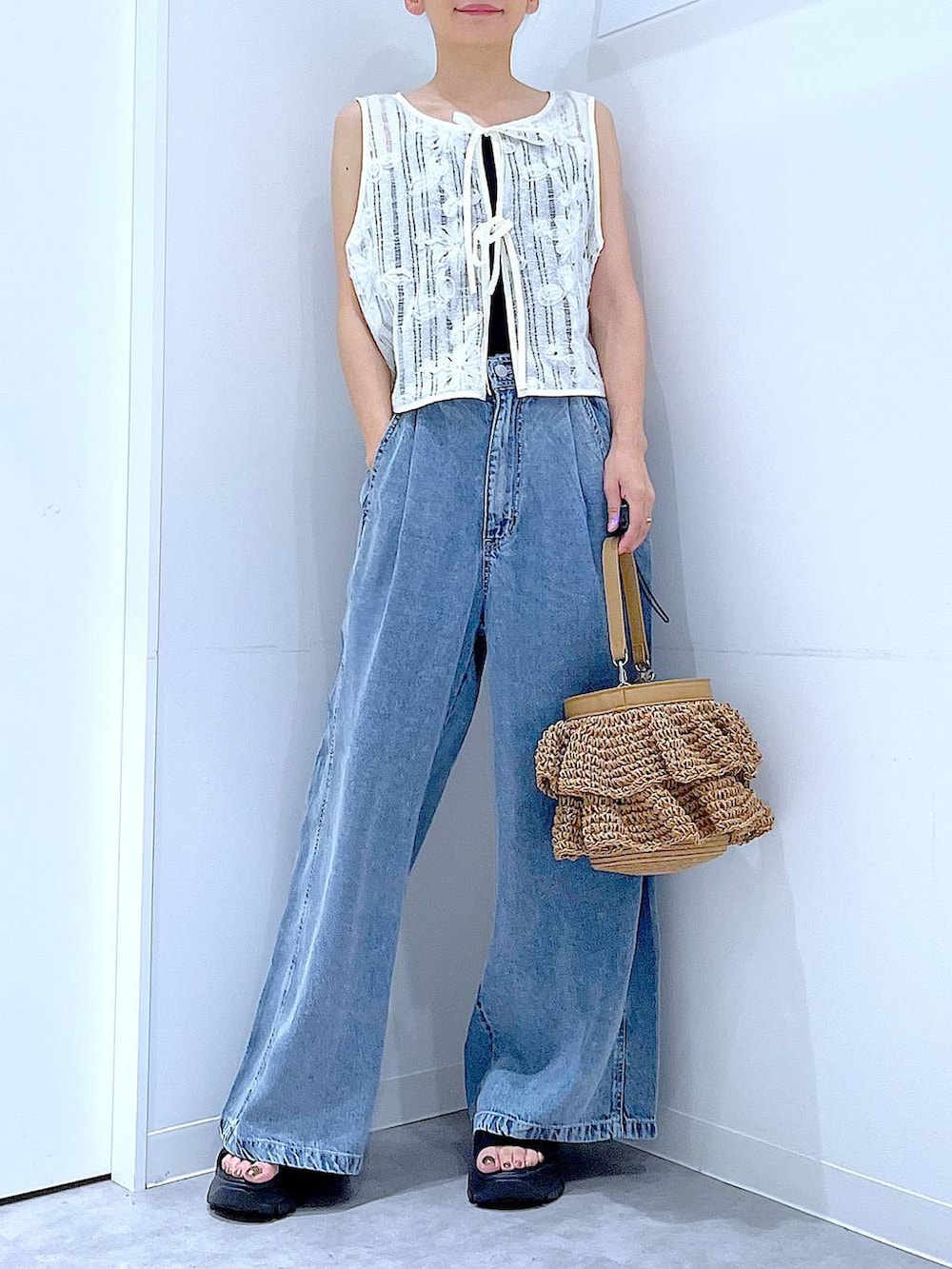 ベージュ系のショルダーバッグ、ブルー系のデニムパンツ、ベージュ系のベストを着用したレディースの夏コーディネートの6枚目の写真