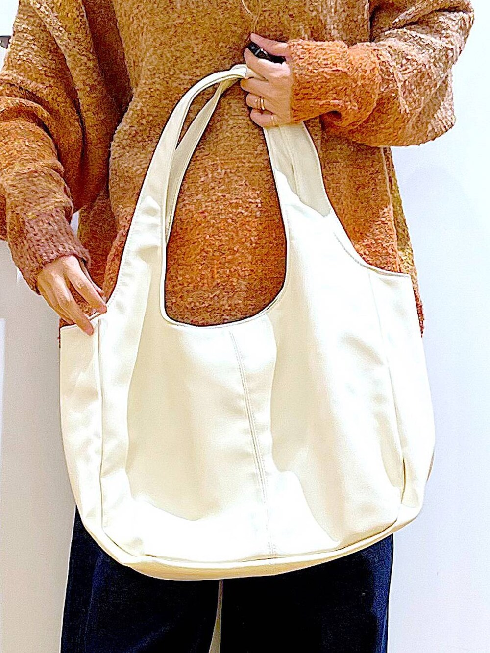 オレンジ系のニット/セーター、ホワイト系のトートバッグ、ベージュ系のブーツを着用したレディースの冬コーディネートの9枚目の写真