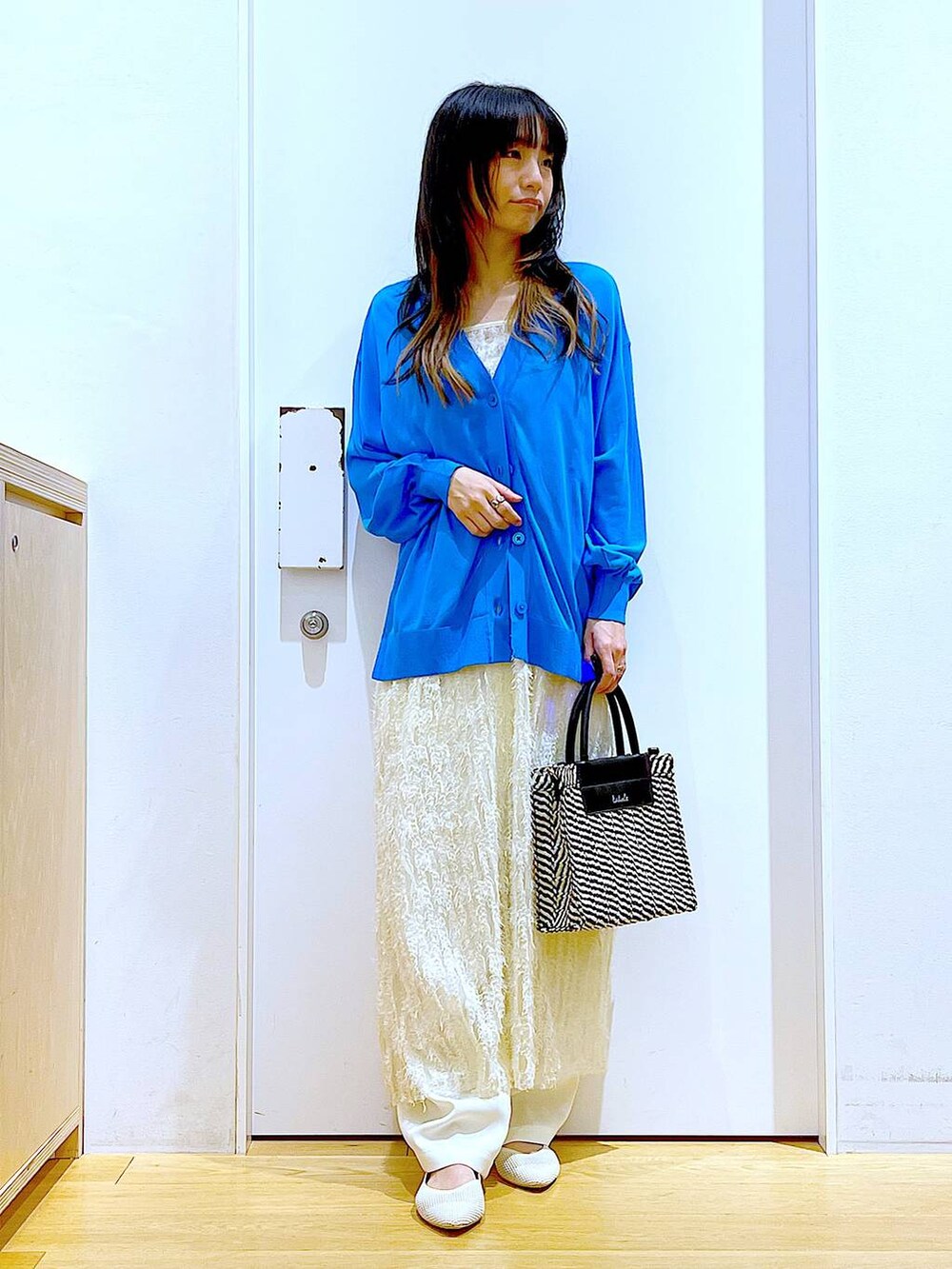 ホワイト系のその他パンツ、ブルー系のカーディガン/ボレロ、ホワイト系のパンプスを着用したレディースの春コーディネートの2枚目の写真