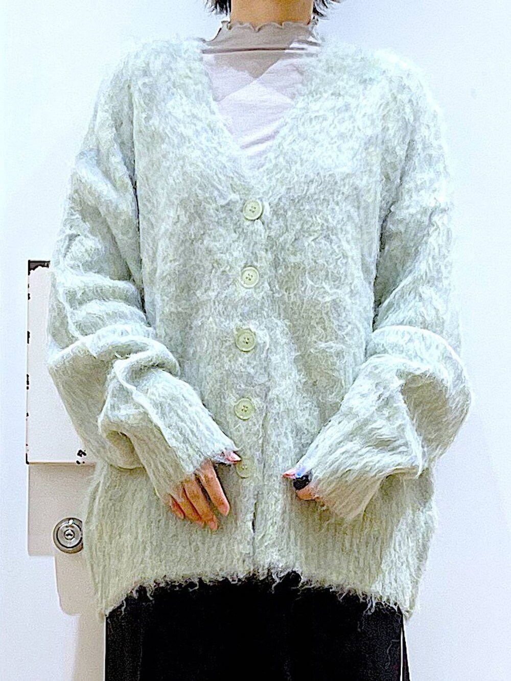 グリーン系のカーディガン/ボレロ、ブラック系のスラックス、ブラック系のショルダーバッグを着用したレディースの冬コーディネートの7枚目の写真