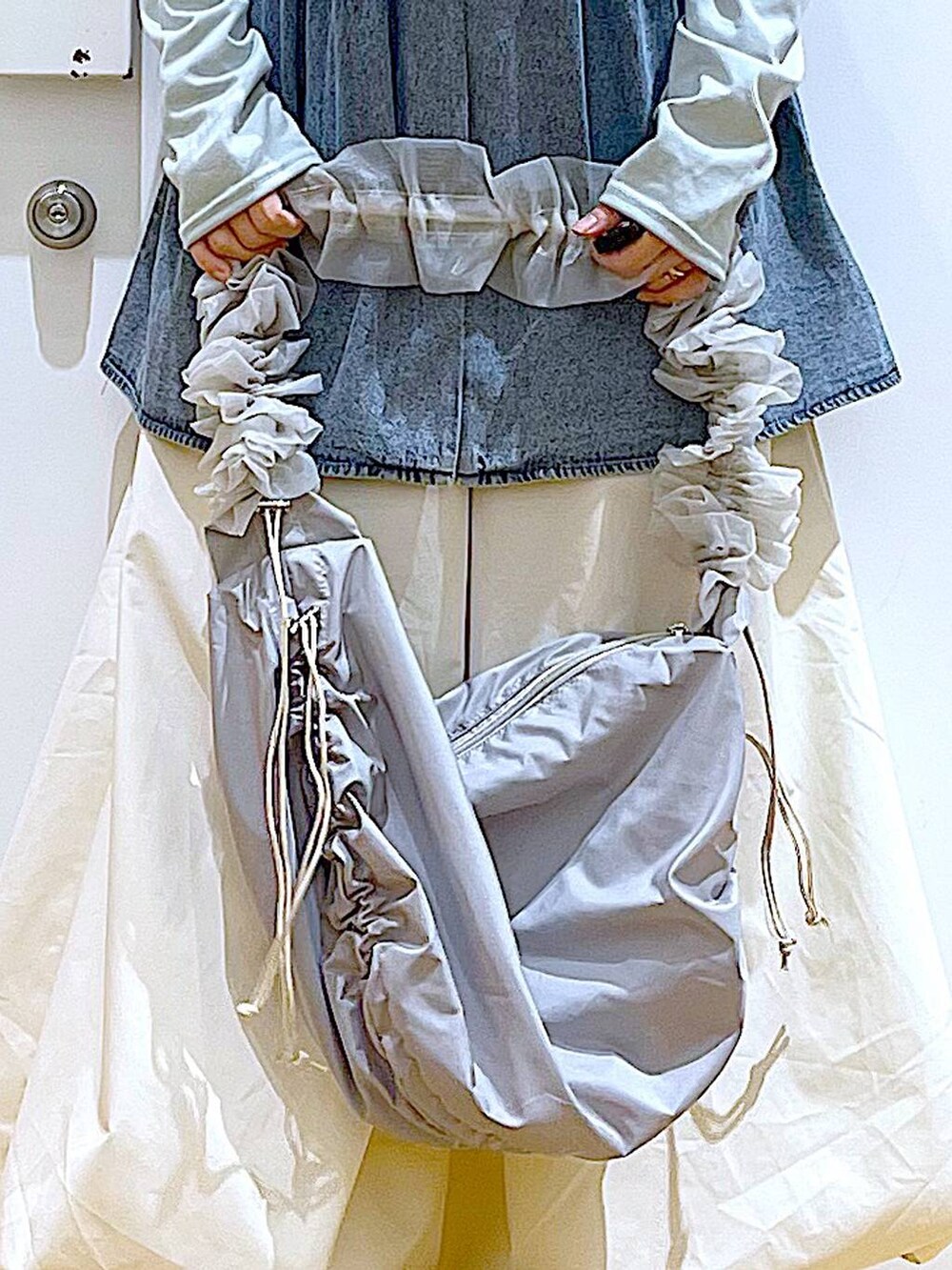 グレー系のショルダーバッグ、ブラック系のスニーカー、ブルー系のその他トップスを着用したレディースの春コーディネートの9枚目の写真