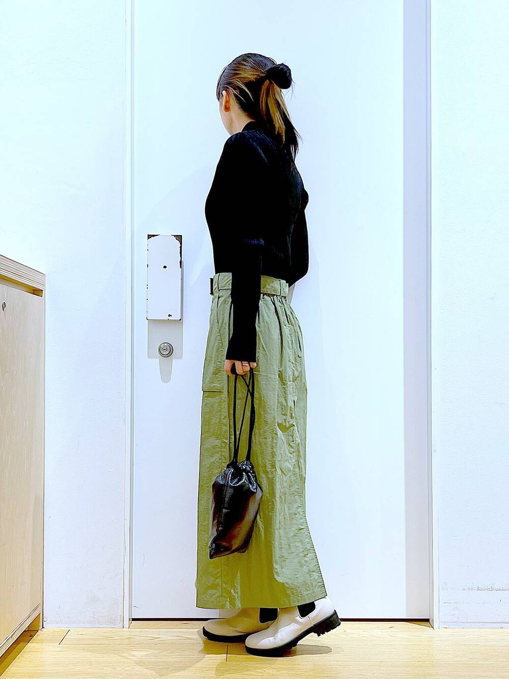 ブラック系のカーディガン/ボレロ、ベージュ系のブーツ、ブラック系のショルダーバッグを着用したレディースの春コーディネートの3枚目の写真