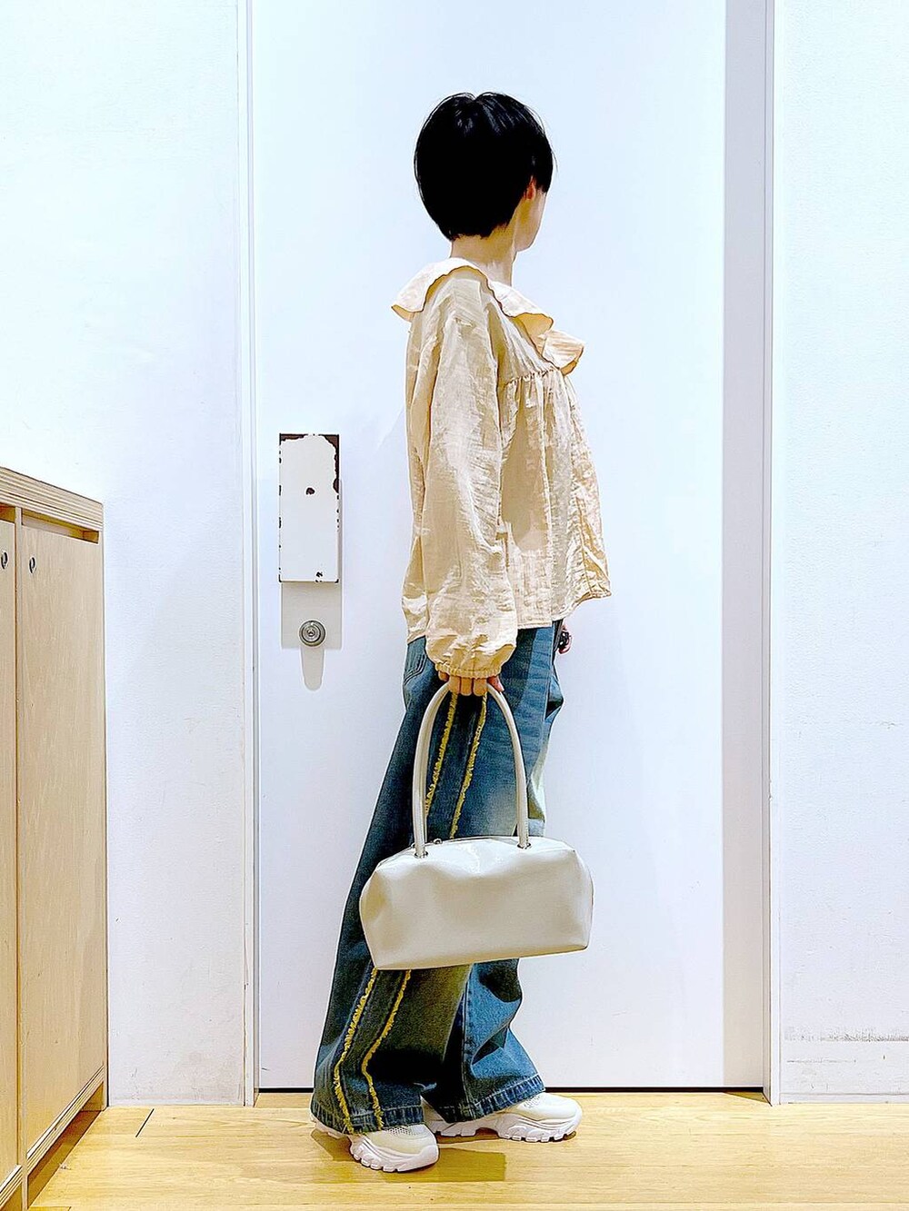 ホワイト系のボストンバッグ、ホワイト系のスニーカー、ブルー系のデニムパンツを着用したレディースの春コーディネートの4枚目の写真
