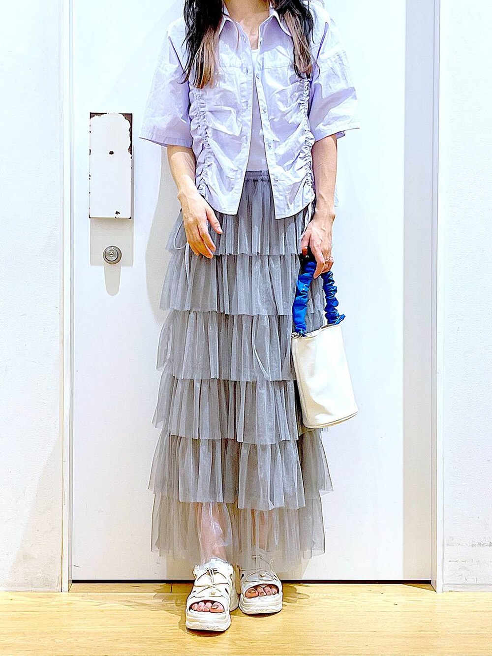 ブルー系のショルダーバッグ、ホワイト系のサンダル、グレー系のスカートを着用したレディースの夏コーディネートの6枚目の写真