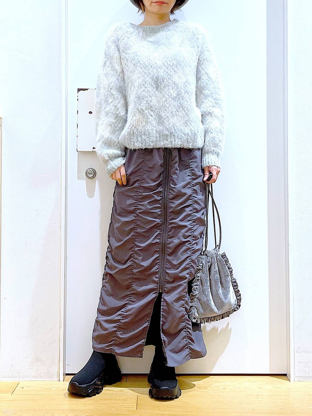 グレー系のショルダーバッグ、グレー系のスカート、ブラック系のブーツを着用したレディースの冬コーディネートの6枚目の写真