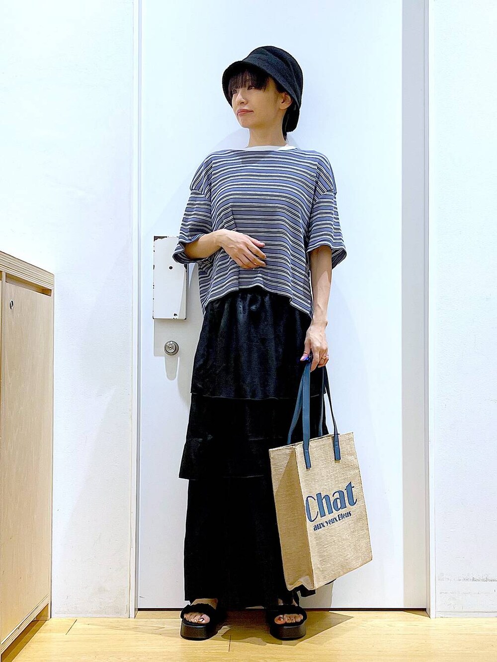 ブラック系のサンダル、グレー系のTシャツ/カットソー、ブルー系のトートバッグを着用したレディースの夏コーディネートの2枚目の写真