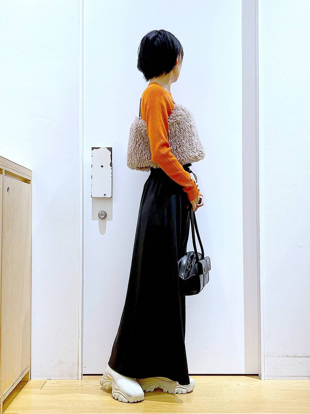 オレンジ系のニット/セーター、ブラウン系のベスト、ブラック系のハンドバッグを着用したレディースの秋コーディネートの4枚目の写真