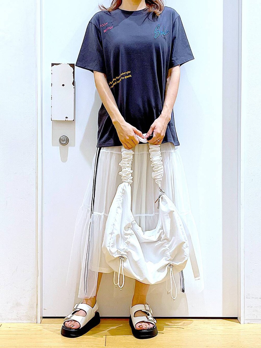 ホワイト系のサンダル、ホワイト系のショルダーバッグ、ホワイト系のスカートを着用したレディースの夏コーディネートの3枚目の写真