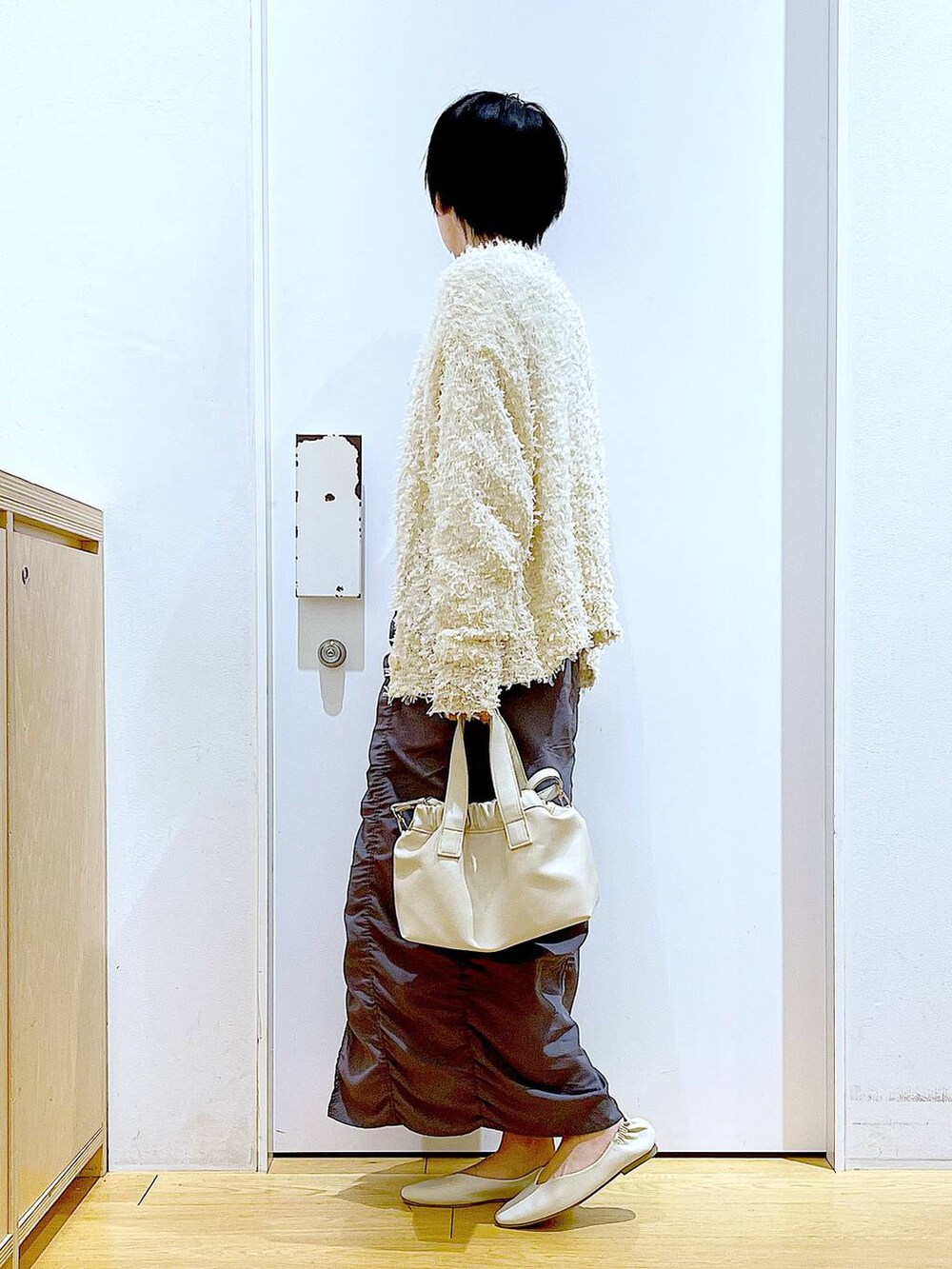 グレー系のスカート、ホワイト系のショルダーバッグ、ホワイト系のパンプスを着用したレディースの春コーディネートの3枚目の写真