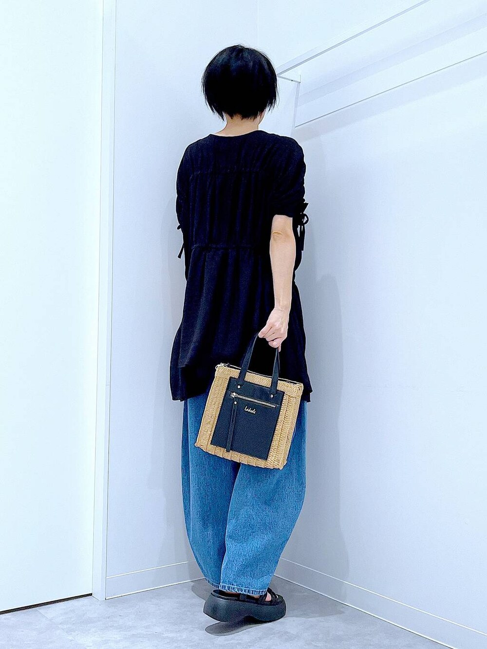 ブルー系のデニムパンツ、ベージュ系のショルダーバッグ、ブラック系のサンダルを着用したレディースの夏コーディネートの5枚目の写真