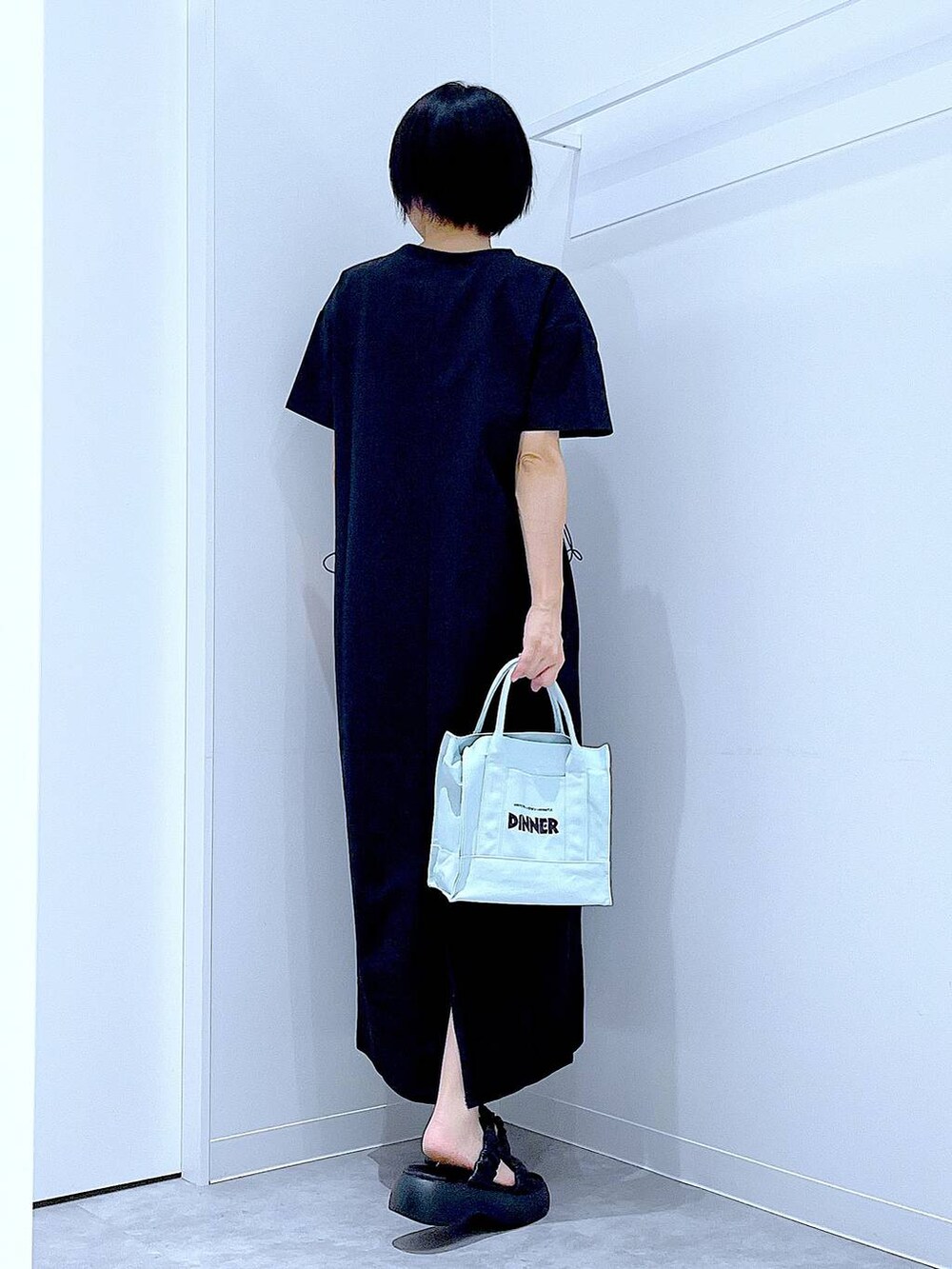 ブラック系のサンダル、ブラック系のワンピース、グリーン系のトートバッグを着用したレディースの夏コーディネートの5枚目の写真