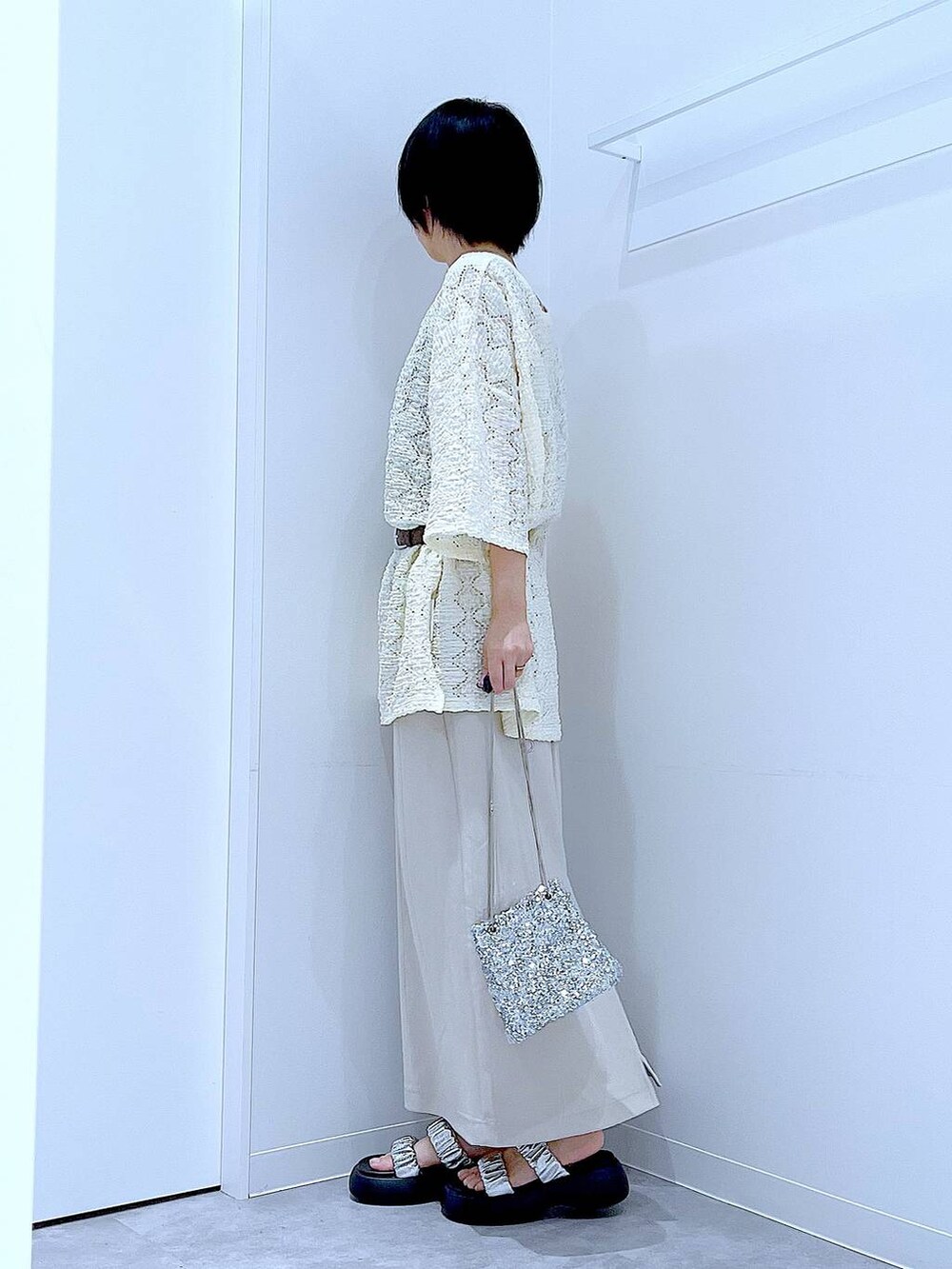 シルバー系のサンダル、ベージュ系のスカート、シルバー系のショルダーバッグを着用したレディースの夏コーディネートの3枚目の写真