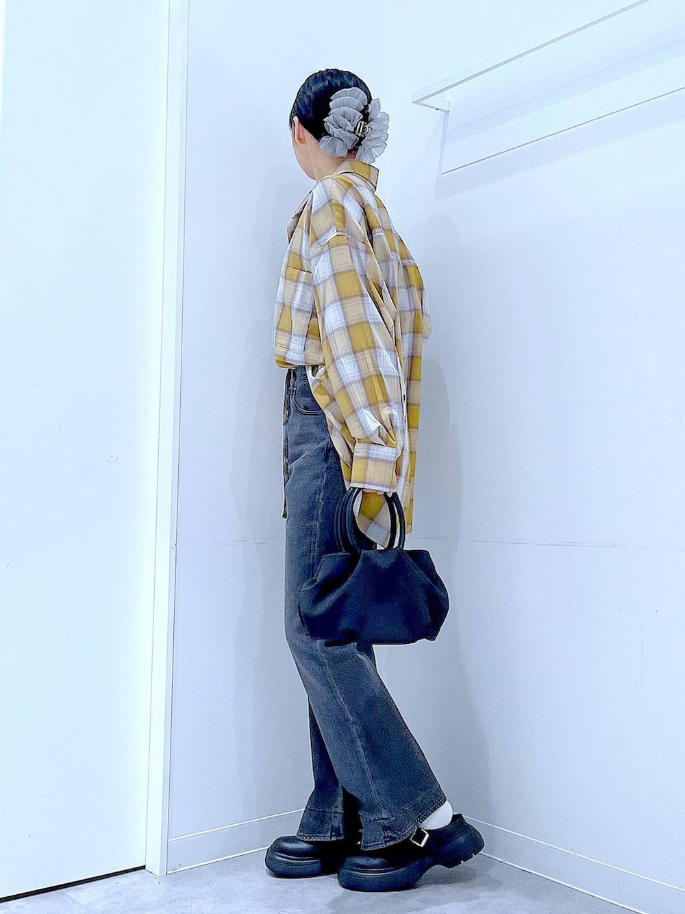 ブラック系のハンドバッグ、ブラック系のデニムパンツ、イエロー系のシャツ/ブラウスを着用したレディースの秋コーディネートの3枚目の写真