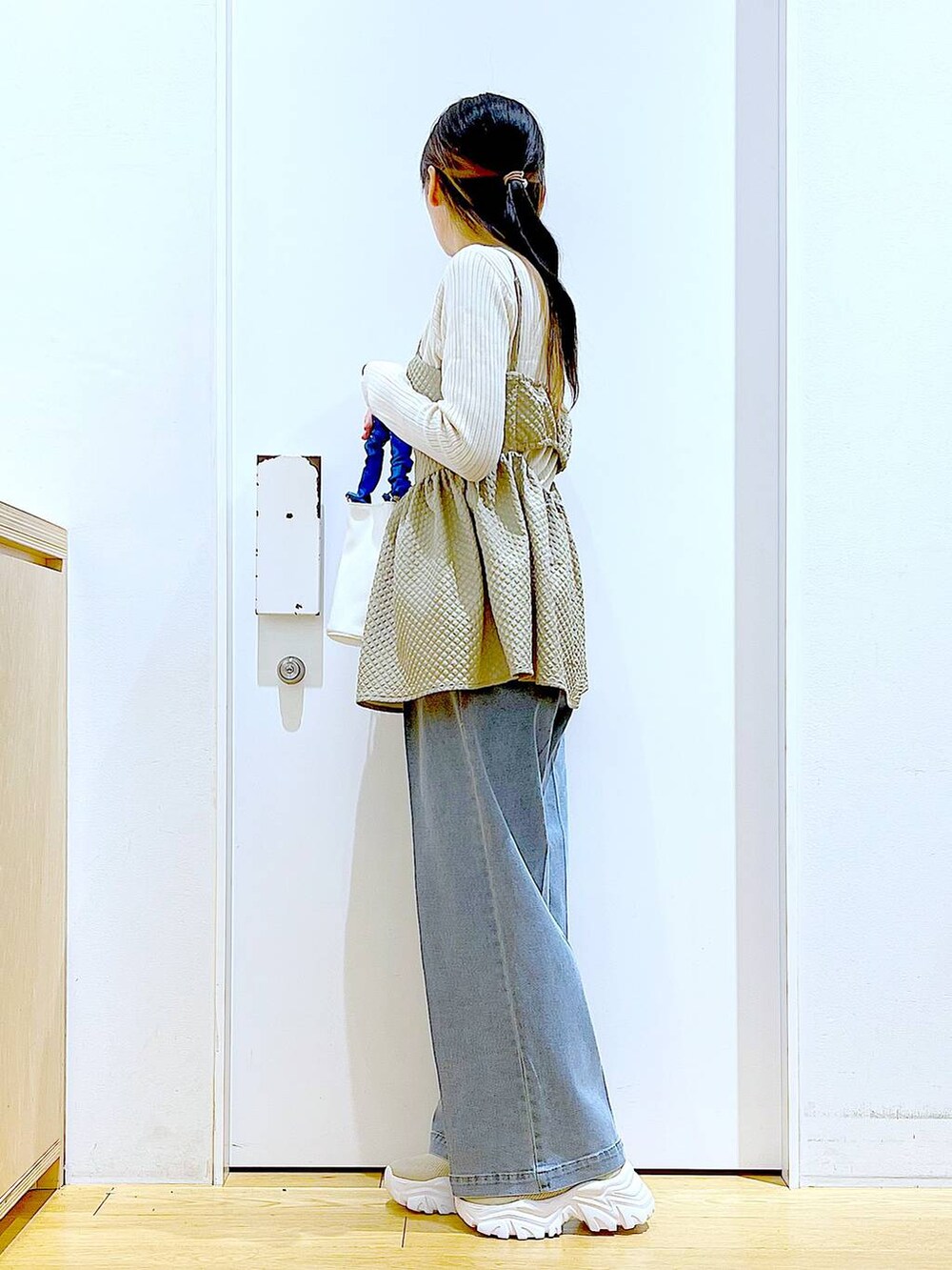 ブルー系のショルダーバッグ、ブルー系のデニムパンツ、ベージュ系のニット/セーターを着用したレディースの春コーディネートの3枚目の写真