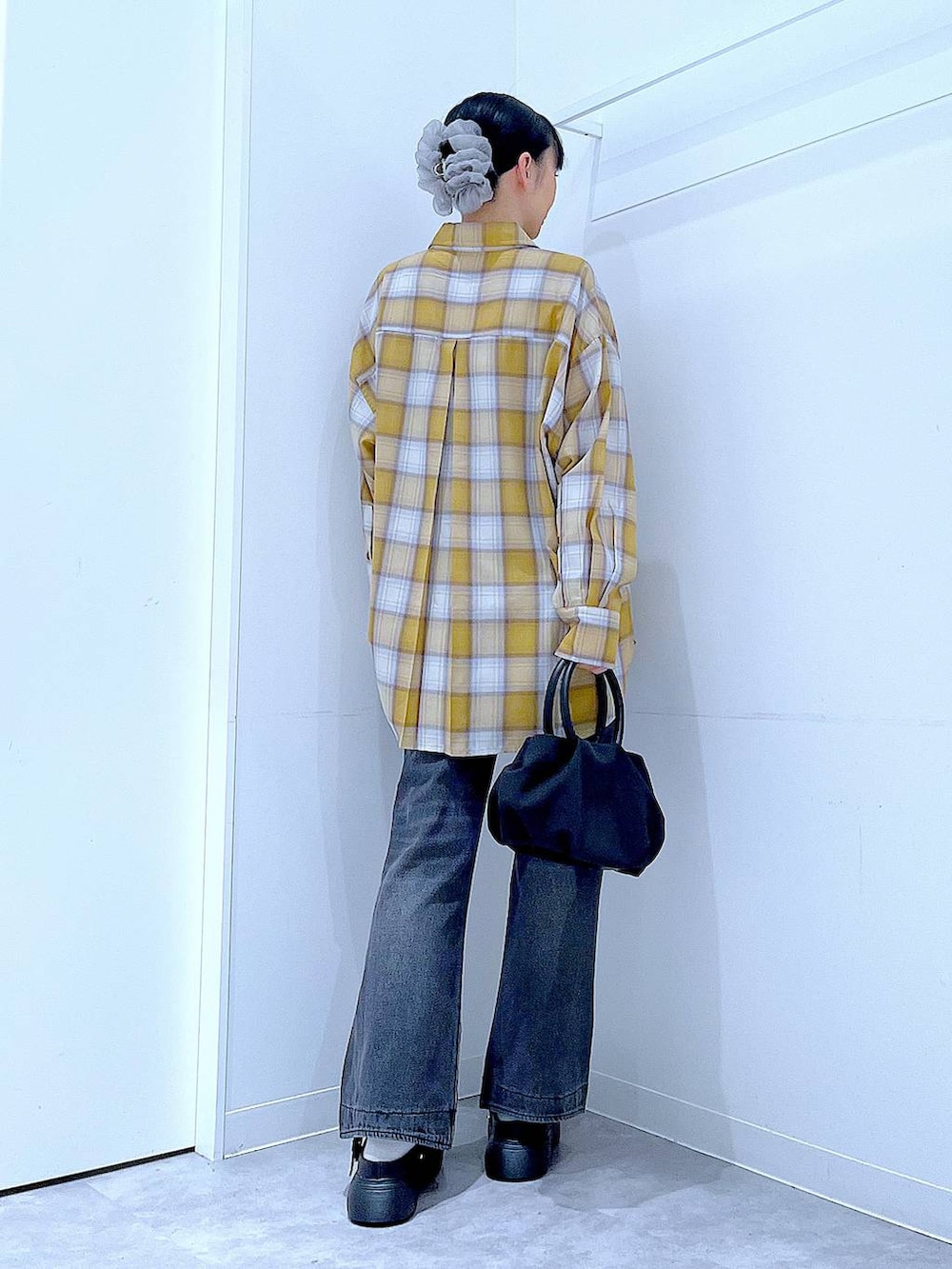 ブラック系のハンドバッグ、ブラック系のデニムパンツ、イエロー系のシャツ/ブラウスを着用したレディースの秋コーディネートの5枚目の写真