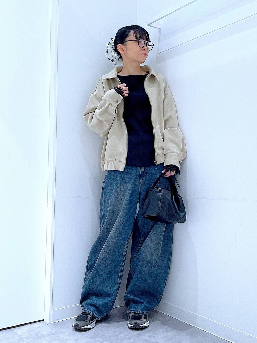 ブルー系のデニムパンツ、ブラック系のショルダーバッグ、ベージュ系のブルゾンを着用したレディースの春コーディネートの2枚目の写真