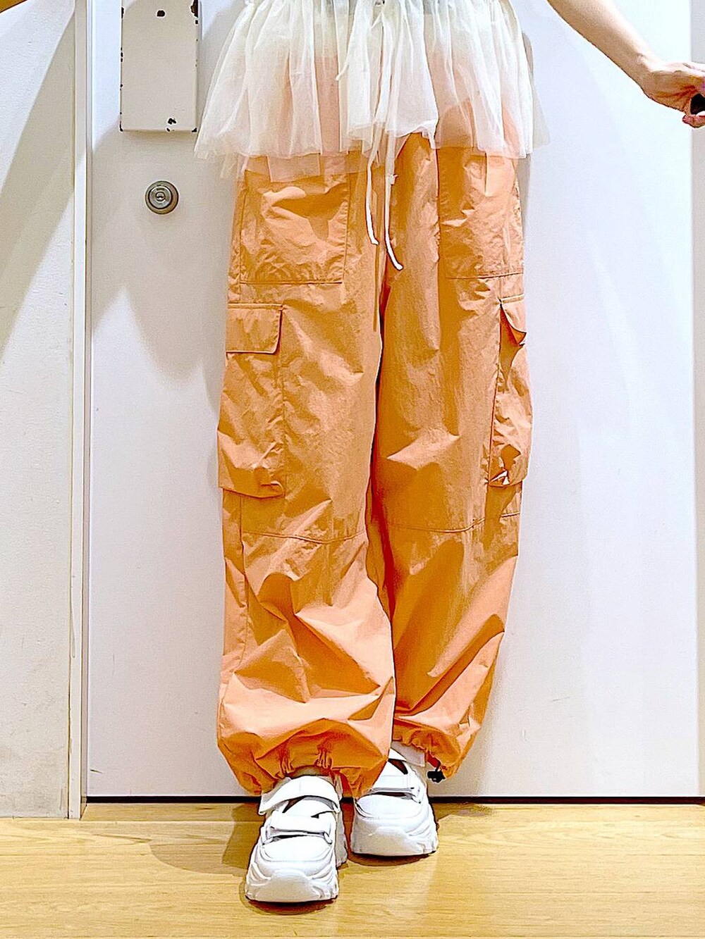 ホワイト系のスニーカー、ホワイト系のショルダーバッグ、オレンジ系のカーゴパンツを着用したレディースの夏コーディネートの9枚目の写真