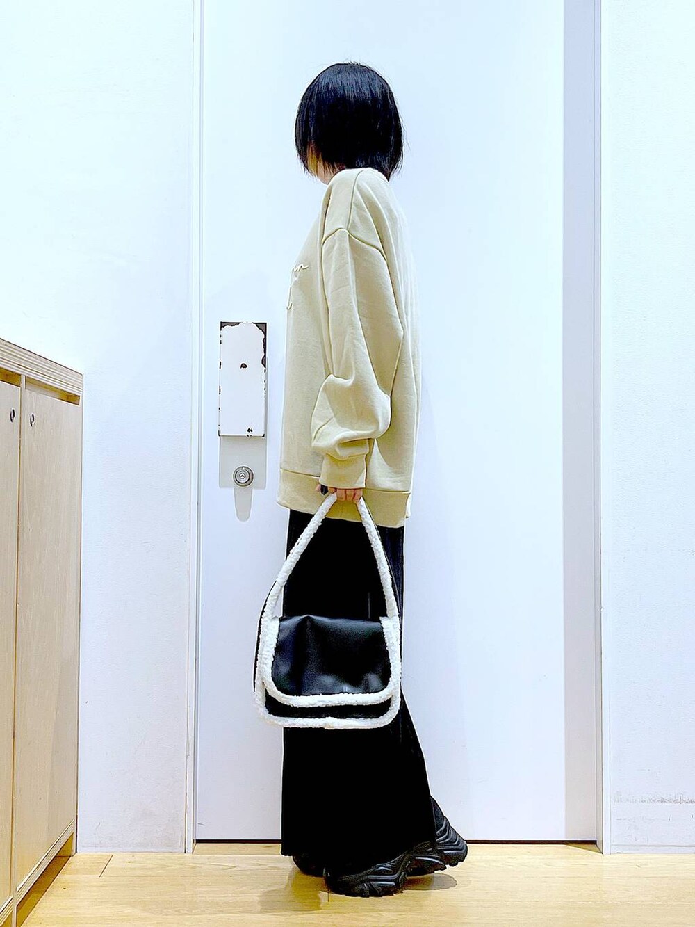 ブラック系のブーツ、ブラック系のショルダーバッグ、ブラック系のスカートを着用したレディースの冬コーディネートの3枚目の写真